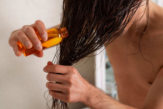 A man applying oil to damp hair at home, showing part of a simple hair care. natural hair oils, scalp care tips