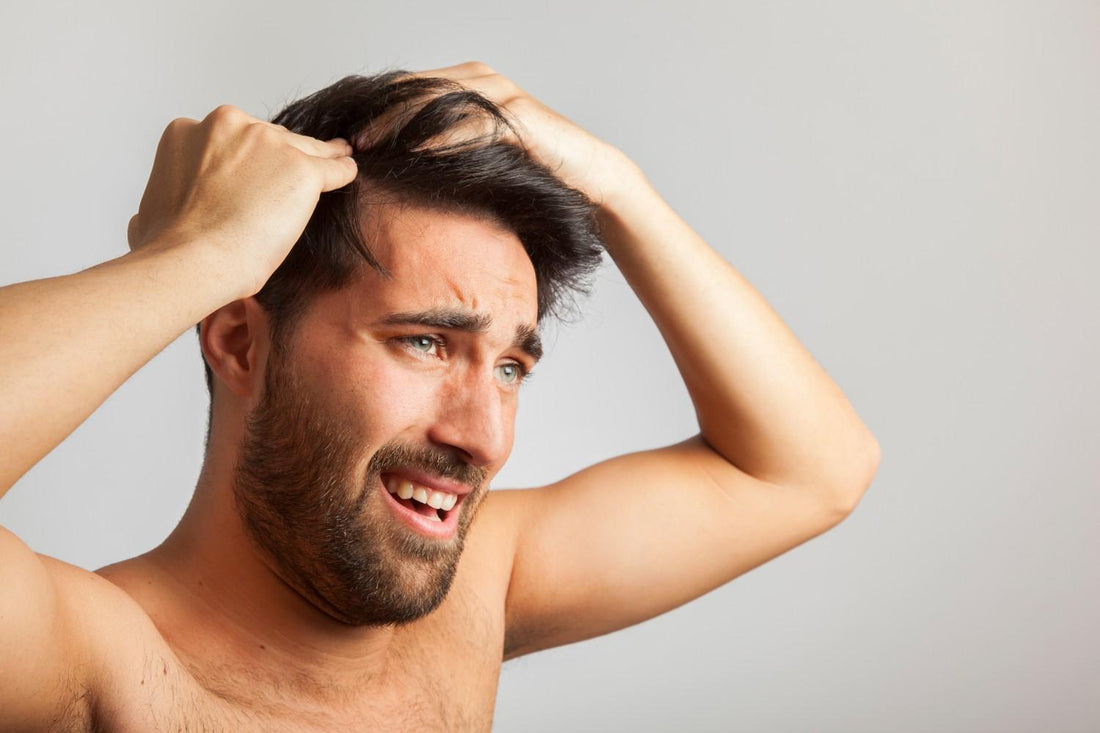 A man touching his thinning hair while examining hair loss. men hair thinning solutions, scalp care routine, natural hair treatments.